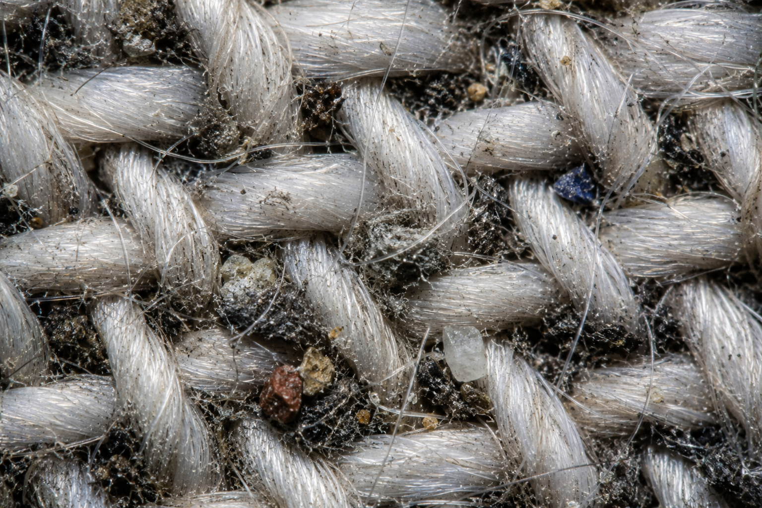 Macro close-up of dust and grit trapped in acoustic fabric weave